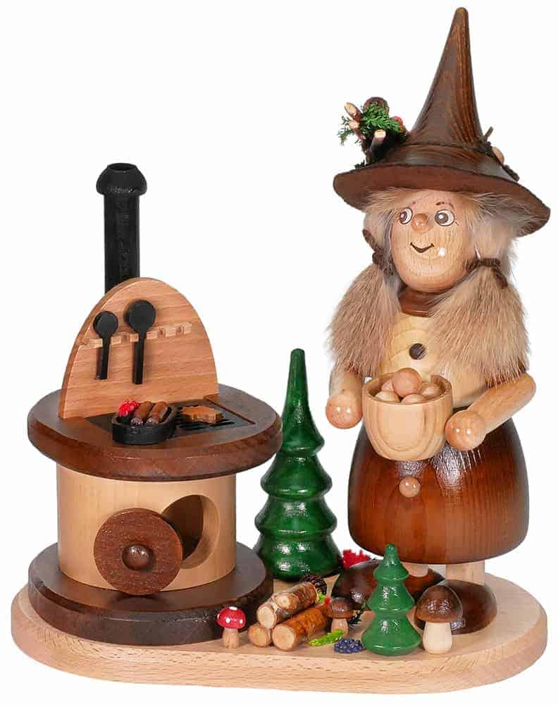 Wooden witch figurine with a cauldron and miniature trees for holiday decor.